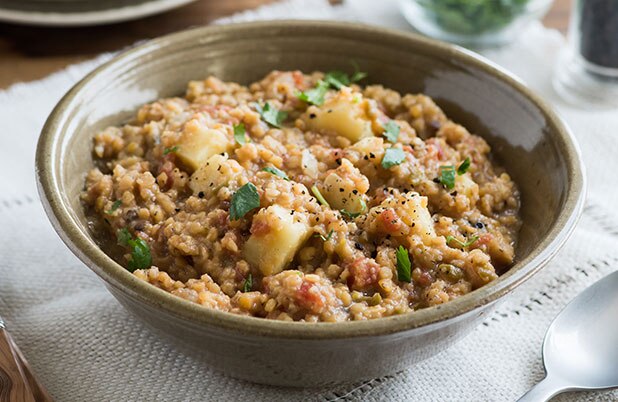 Un tazón de lentejas con chiles jalapeños y camote sobre una servilleta de tela.